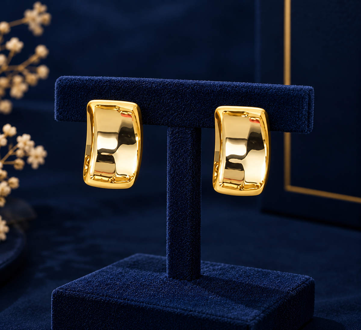 Gold-Tone Wide Curved Huggie Earrings on navy velvet display