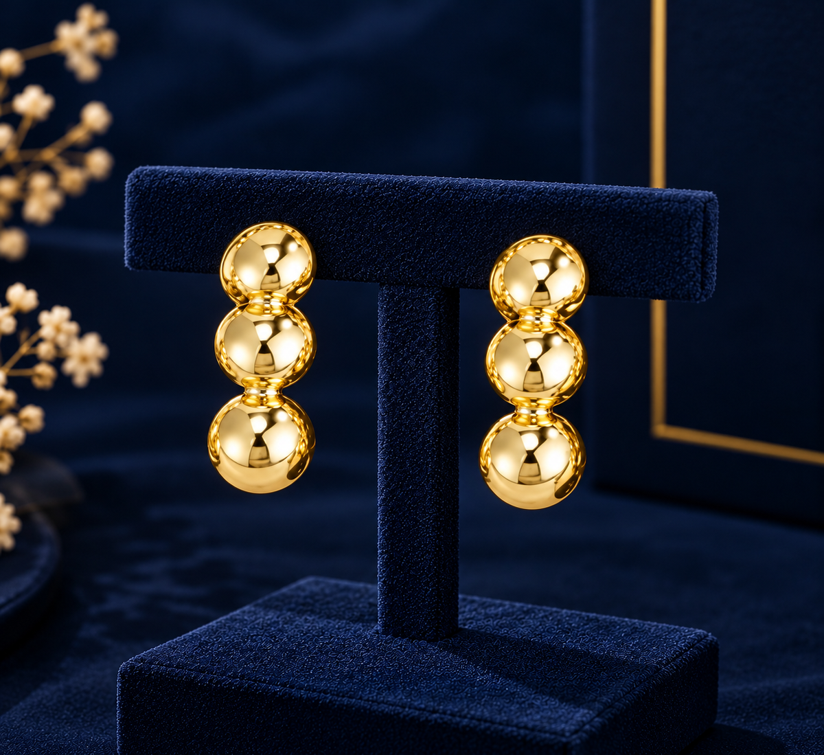 Gold-Tone Triple Bead Drop Earrings on navy velvet display